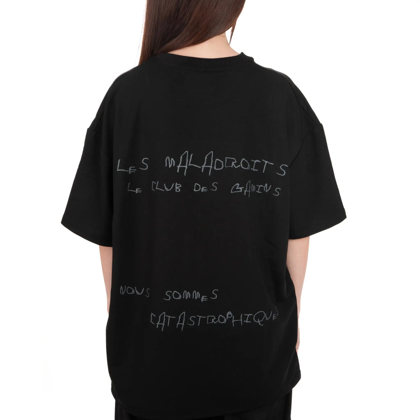 Unisex Oversized Black T-shirt Nous Sommes Catastrophiques back view on female model