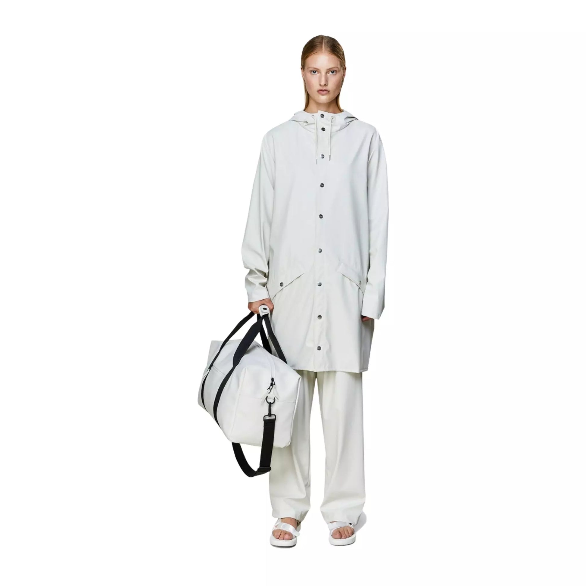 Rains waterproof gym bag off white held by one hand of a woman on the side