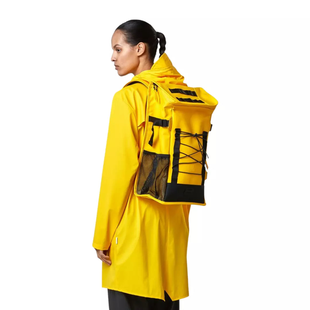 Rains waterproof hiking mountaineer bag yellow worn on the back of a woman