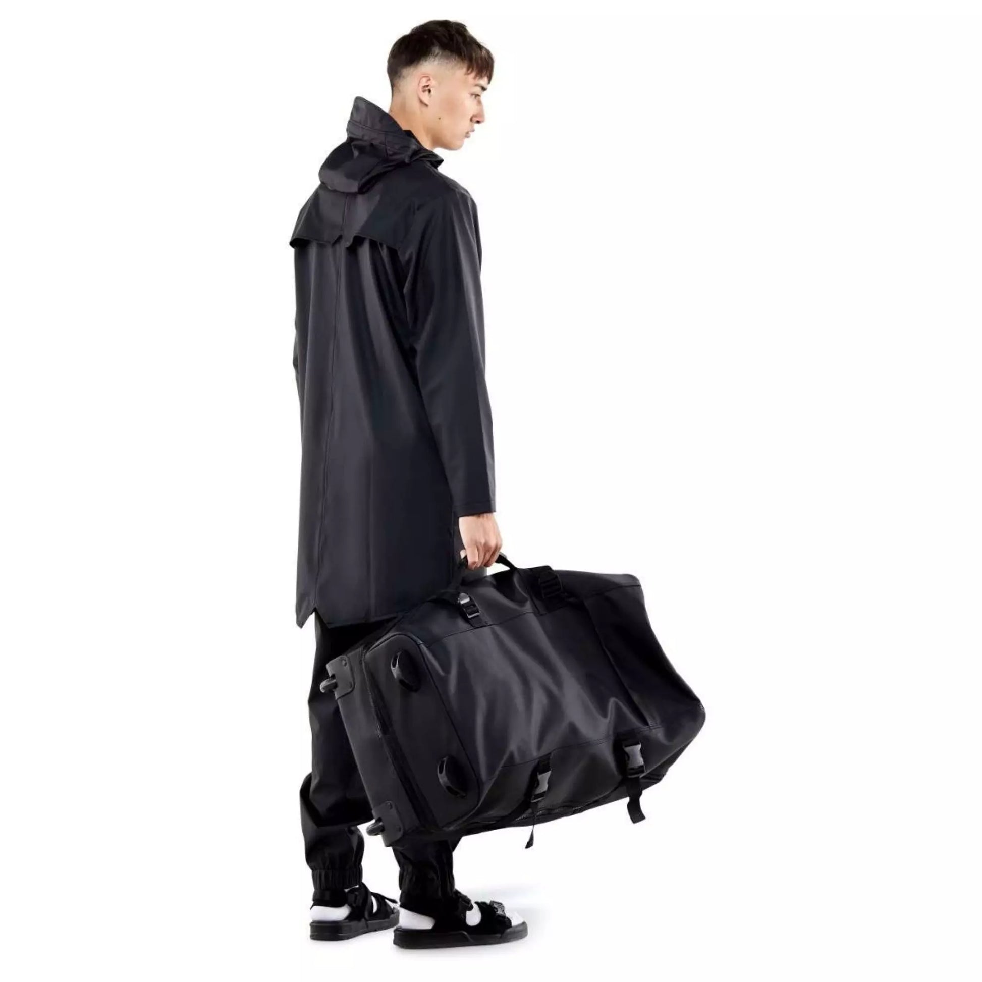 Rains waterproof travel bag large black held by a man